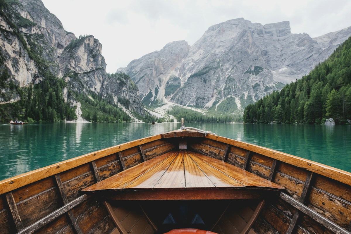 A wooden boat on a calm lake surrounded by mountains